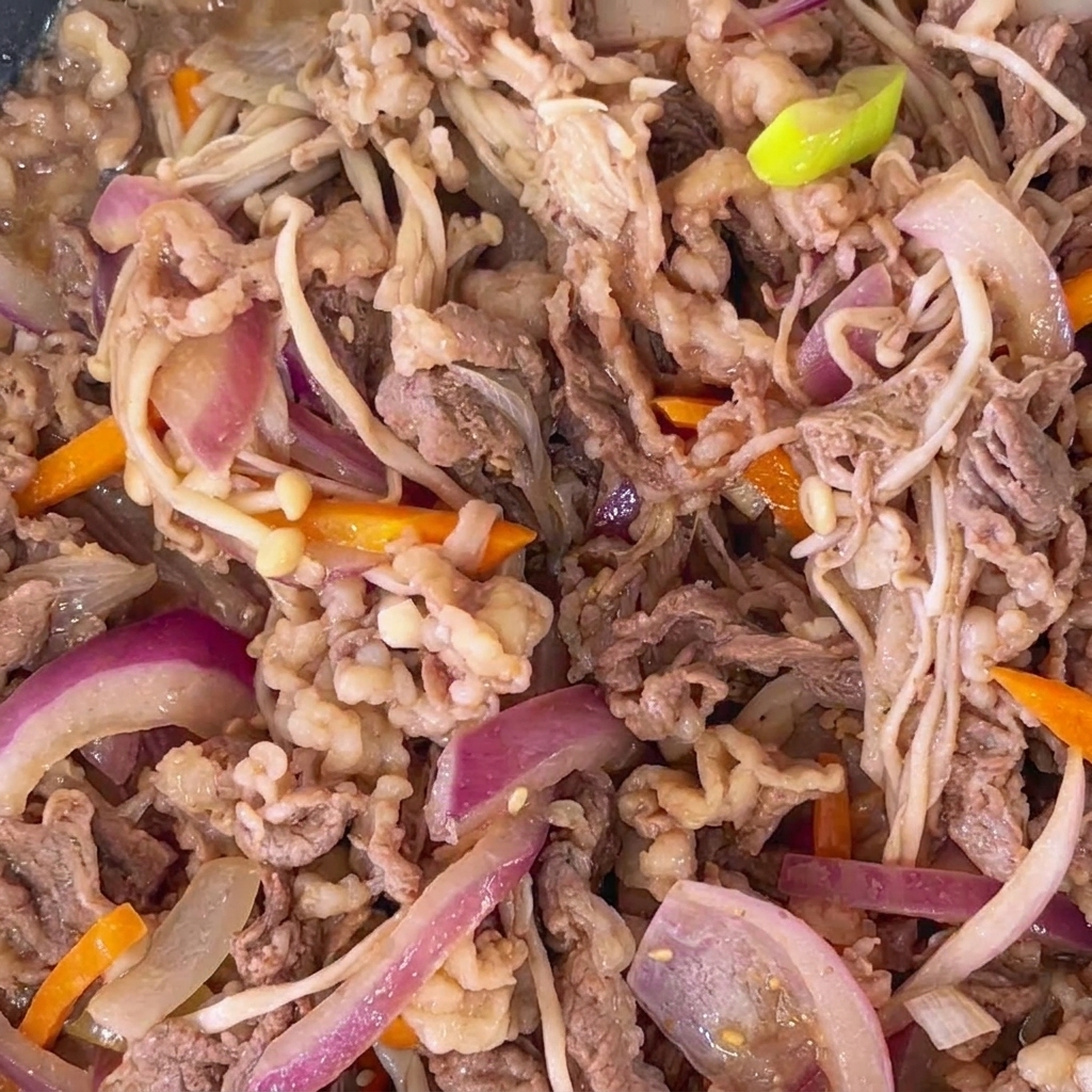 Primo piano di bulgogi di manzo cotto con semi di sesamo tostati sparsi su tutto il piatto.