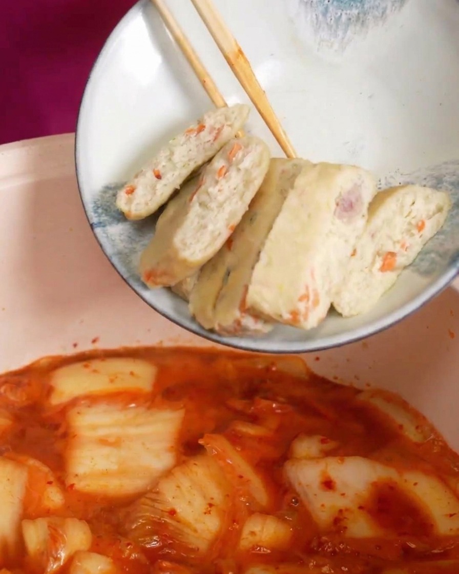 Fette di panetti di pesce immerse nella zuppa di kimchi rossa e bollente.