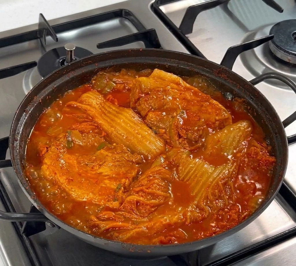 Due spesse fette di pancia di maiale cruda adagiate su un letto di cipolle bianche affettate in una padella nera.