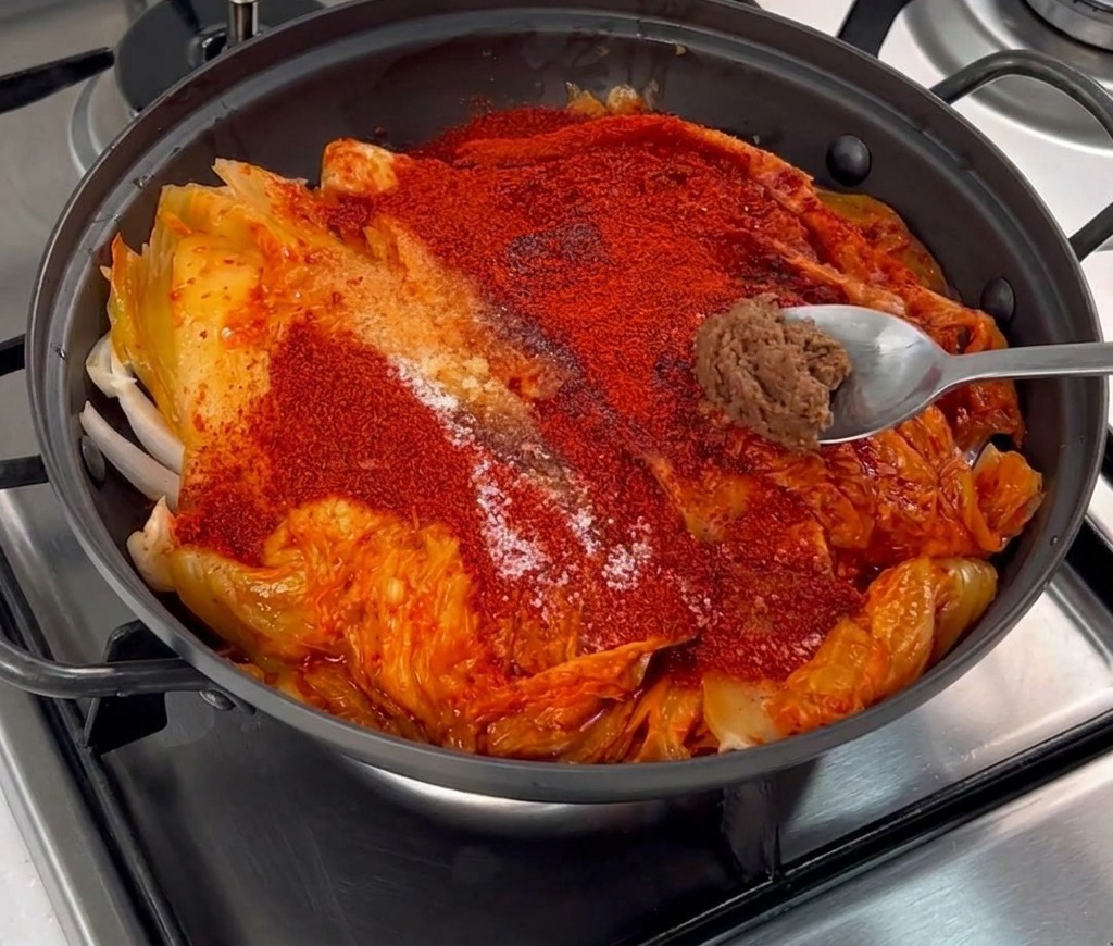 Una piccola dose di densa pasta di soia marrone su un cucchiaio sopra il peperoncino e il kimchi.