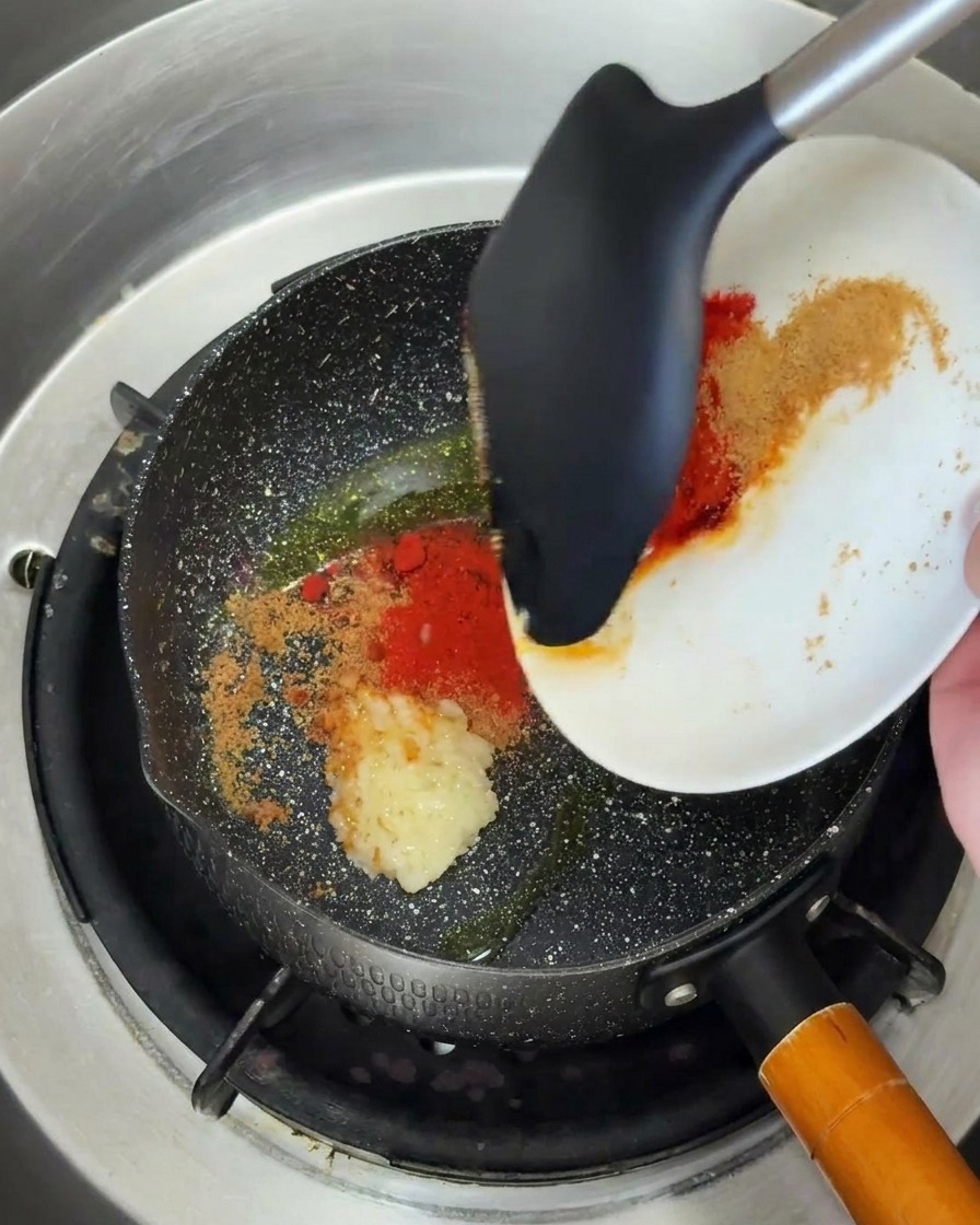 Aglio tritato e polvere di peperoncino versati in una padella calda con olio.