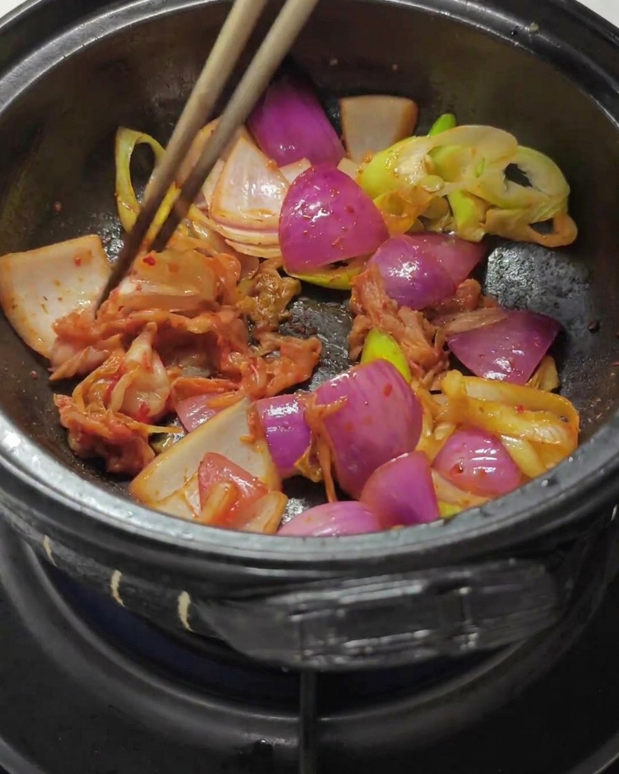 Bacchette che mescolano kimchi tritato e pasta di peperoncino in una pentola.