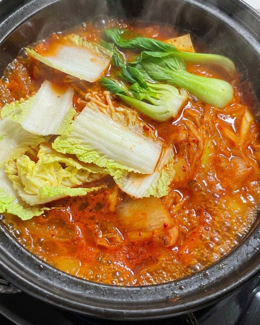 Foglie di cavolo fresco aggiunte a uno stufato rosso ribollente.