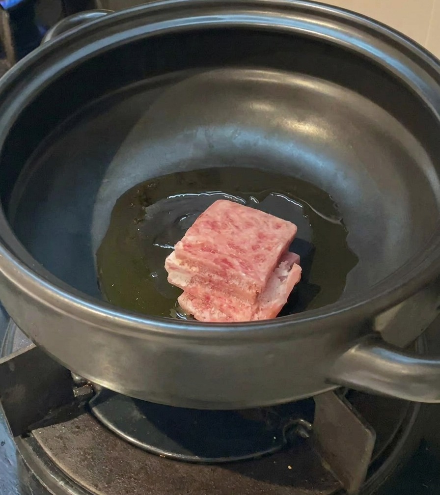 Fette di pancetta di maiale aggiunte nellolio caldo allinterno della pentola.