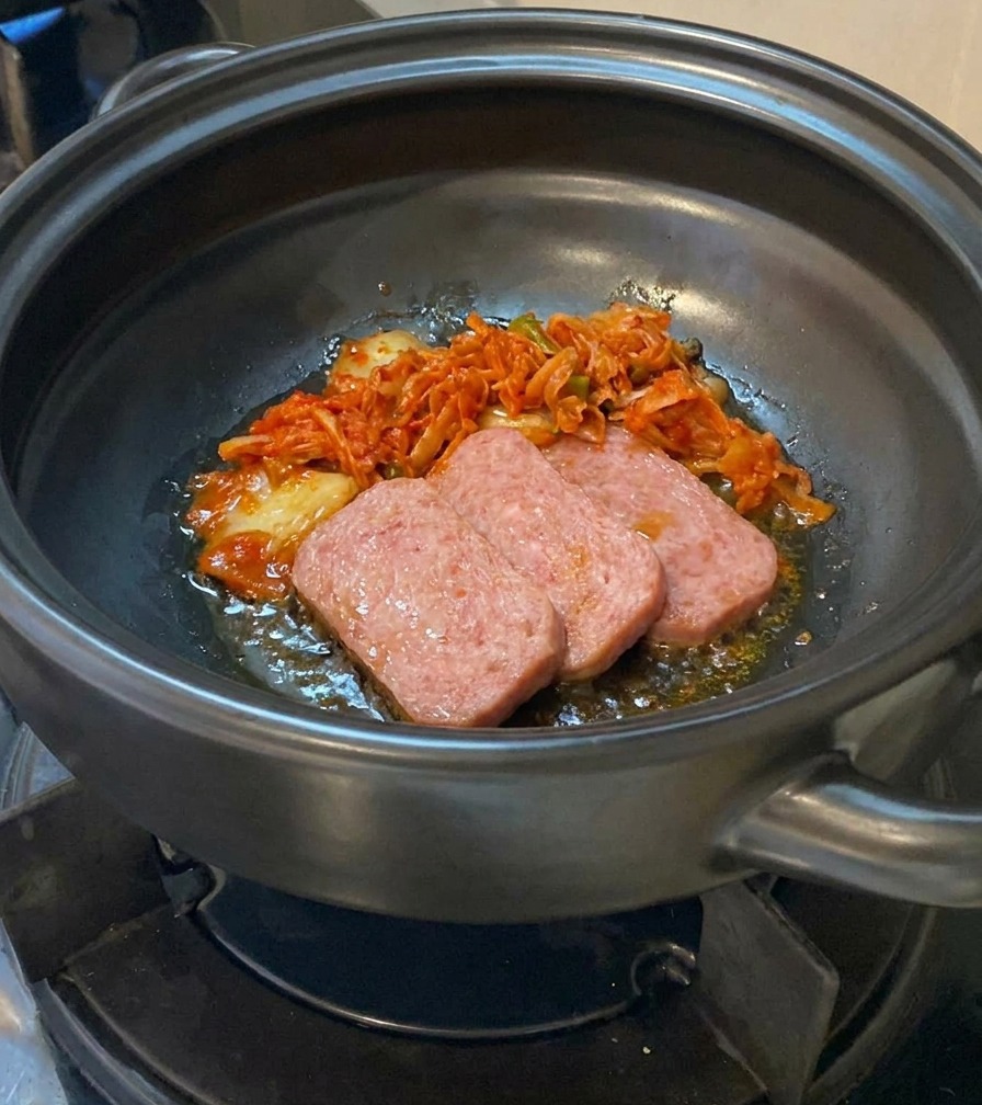 Kimchi tritato aggiunto alla carne rosolata nella pentola di terracotta.