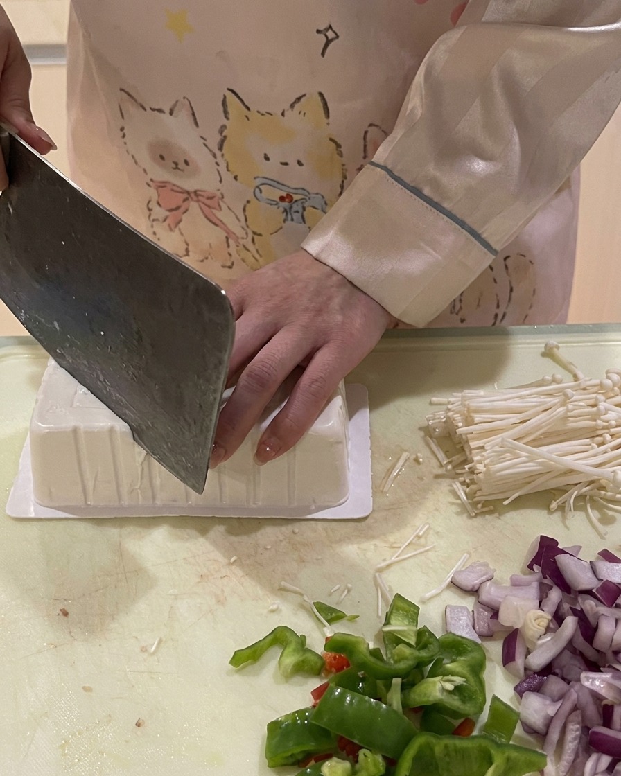 Un coltello che taglia langolo di una confezione di tofu capovolta per facilitarne luscita intatta.