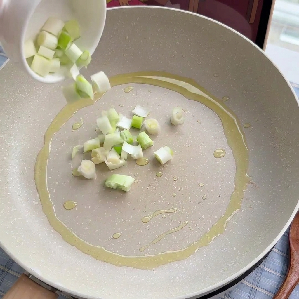Cipollotti e porri tritati che vengono soffritti delicatamente in padella con un filo dolio.
