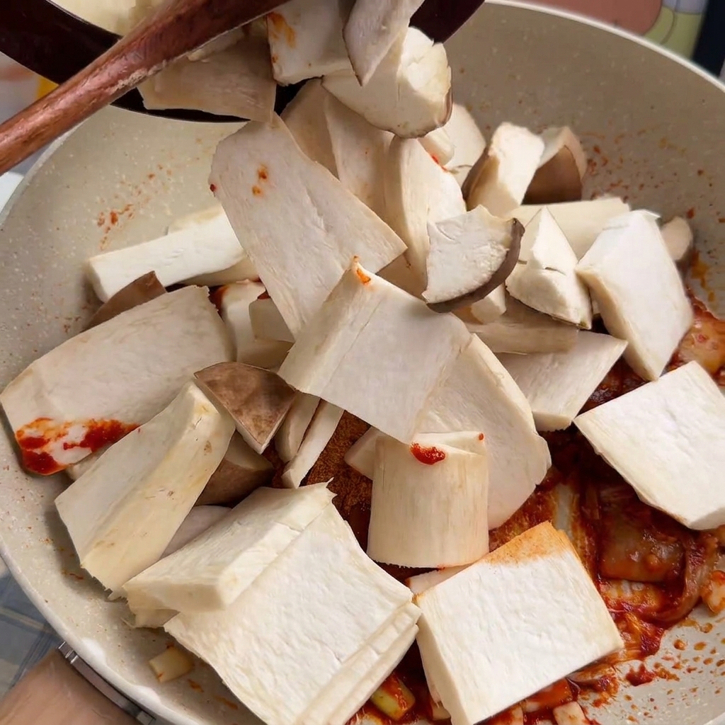 Fette di funghi cardoncelli che vengono aggiunte alla base piccante in padella e mescolate.