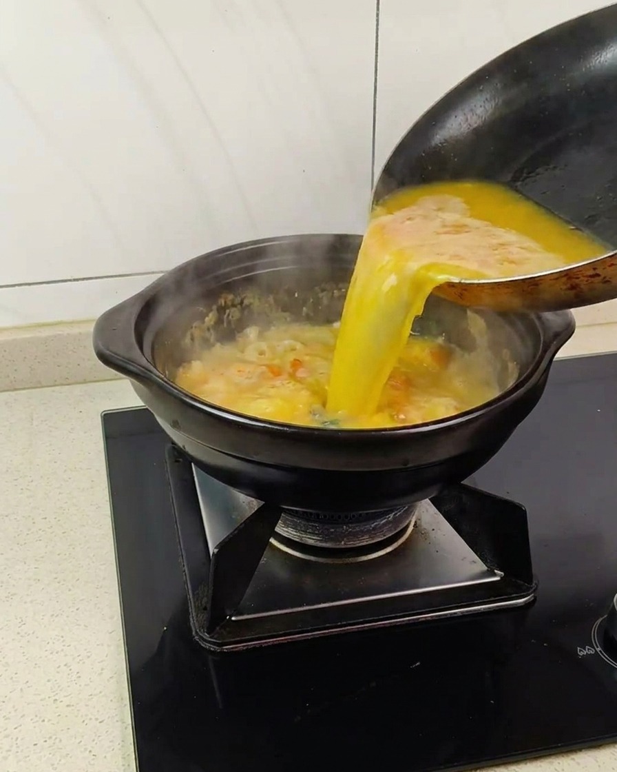 Liquido dorato versato in una pentola con una base di tuorli duovo salati spumosi e bollenti.