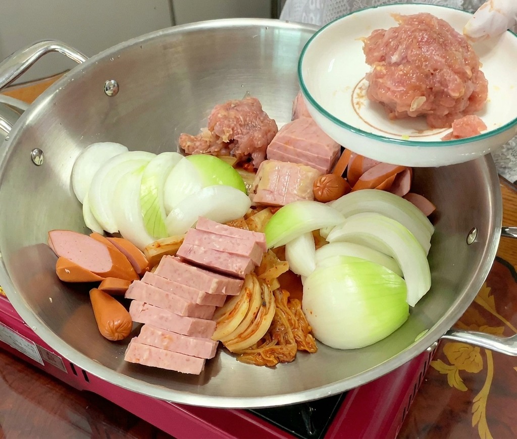 Un cumulo di carne di maiale macinata condita viene aggiunto alla pentola con il resto degli ingredienti.