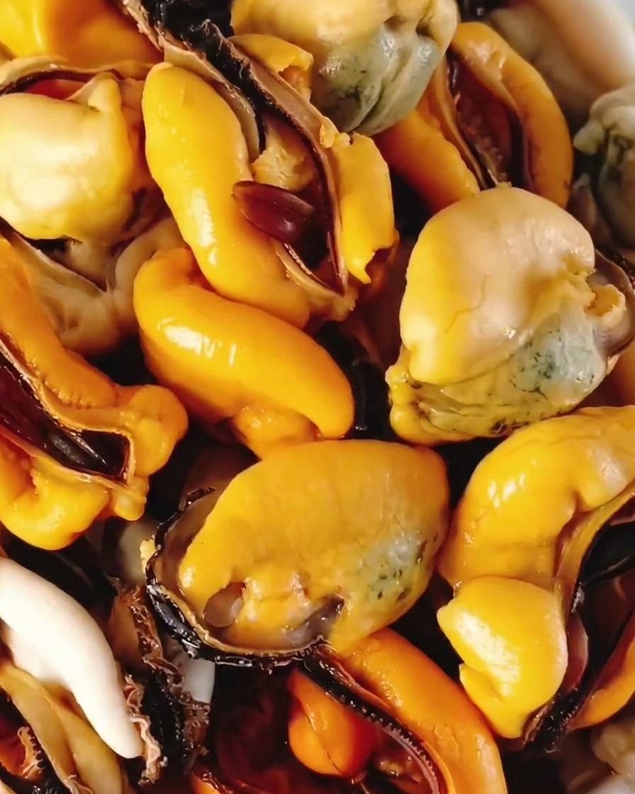 Polpa di cozze cotte estratta dai gusci e raccolta in una ciotola bianca.