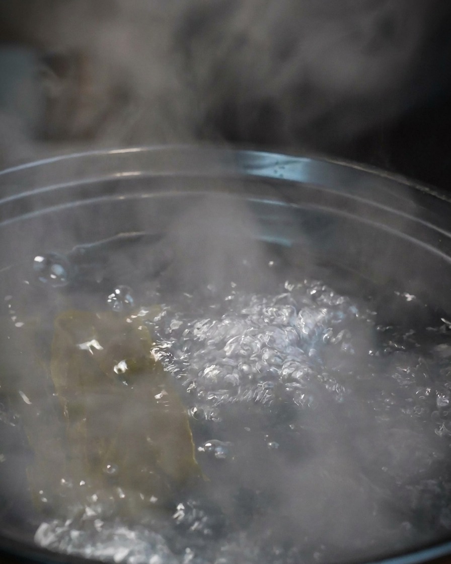 Diversi gamberi grandi crudi che vengono immersi in una pentola dacqua bollente con lalga.