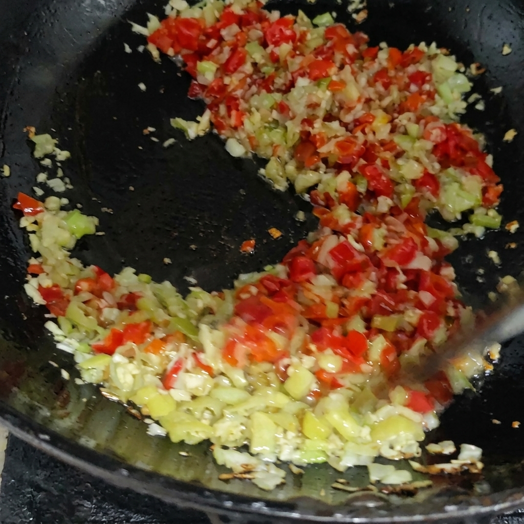 Un mix colorato di peperoncini rossi e verdi tritati saltati con altri aromi in una padella calda.