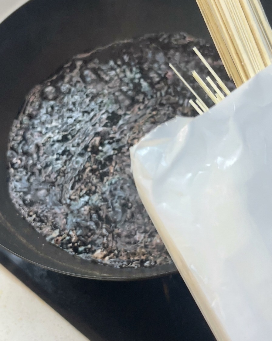 Noodles secchi bianchi immersi in un wok con acqua che bolle vigorosamente.