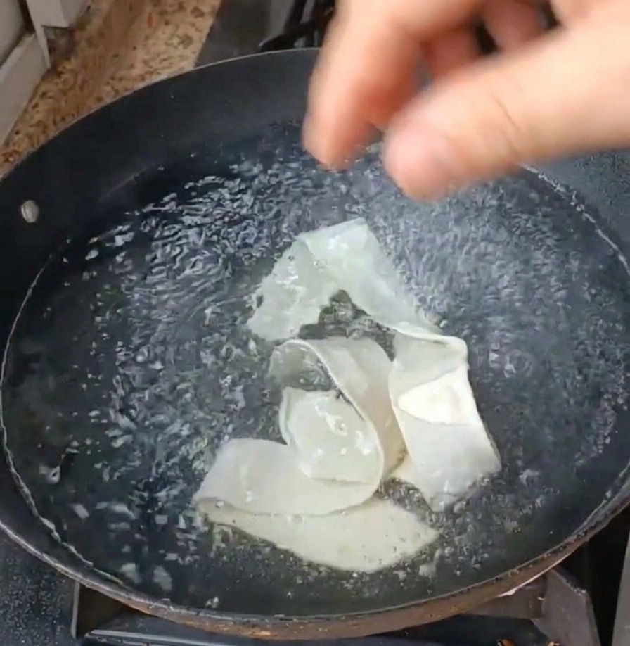 Nastri di pasta e foglie di verdura verde immersi in una pentola di acqua bollente.