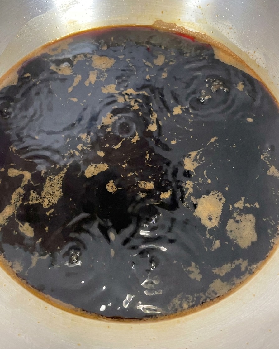 Salsa di soia in una pentola con piccole bollicine in superficie dopo lo spegnimento del fuoco.