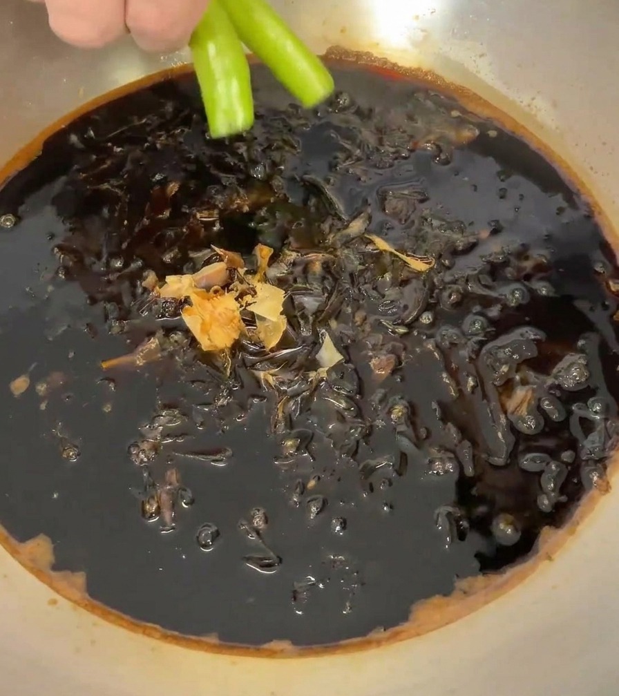 Peperoncini verdi interi immersi nella salsa con fiocchi di katsuobushi.