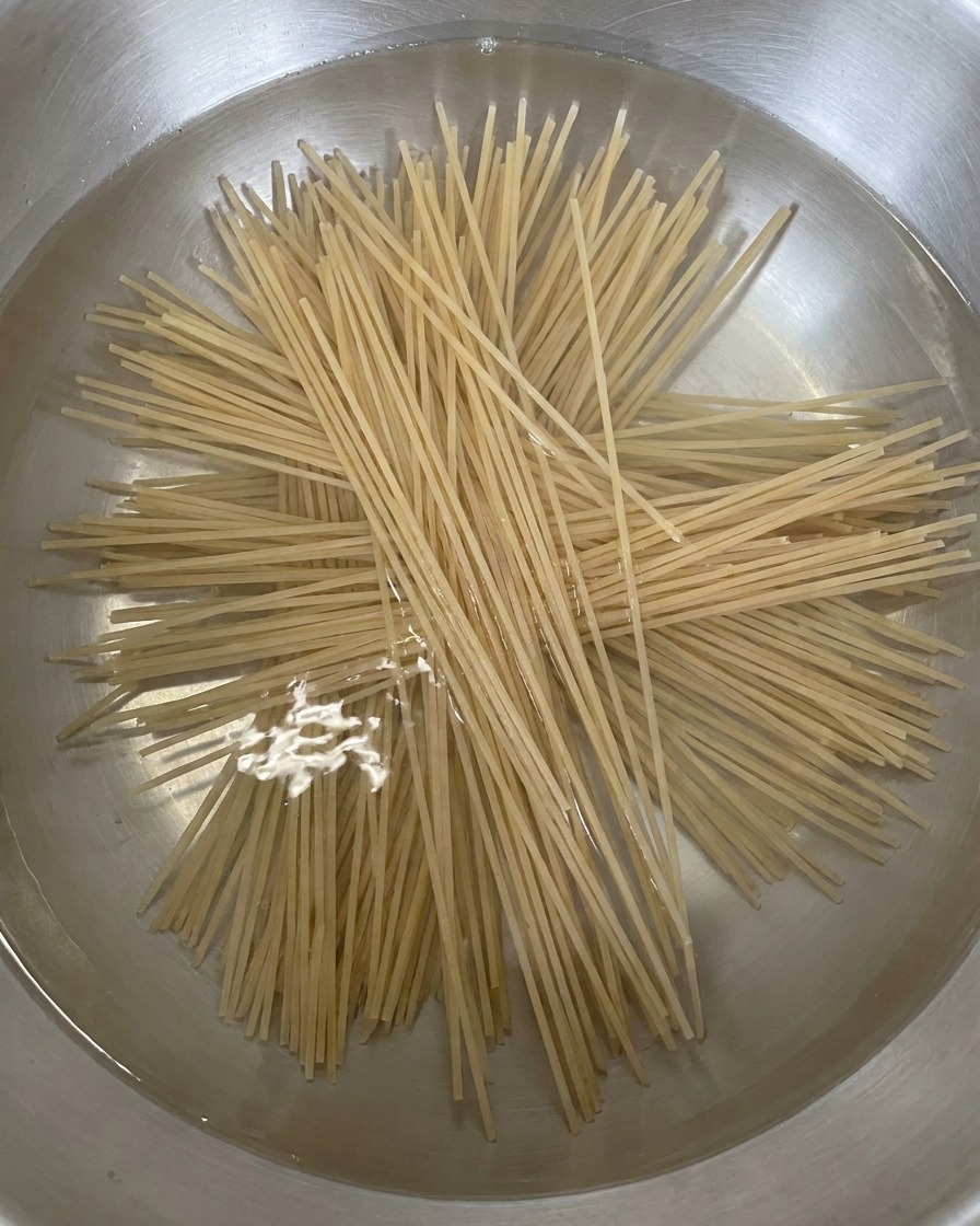 Soba secca disposta a raggiera in una pentola dacqua bollente.