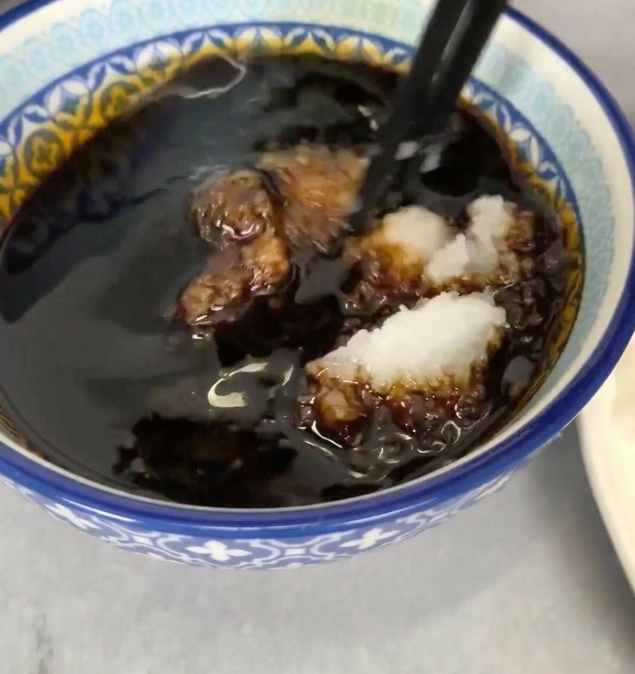 Ciotolina con salsa scura in cui viene mescolato il daikon bianco con le bacchette.