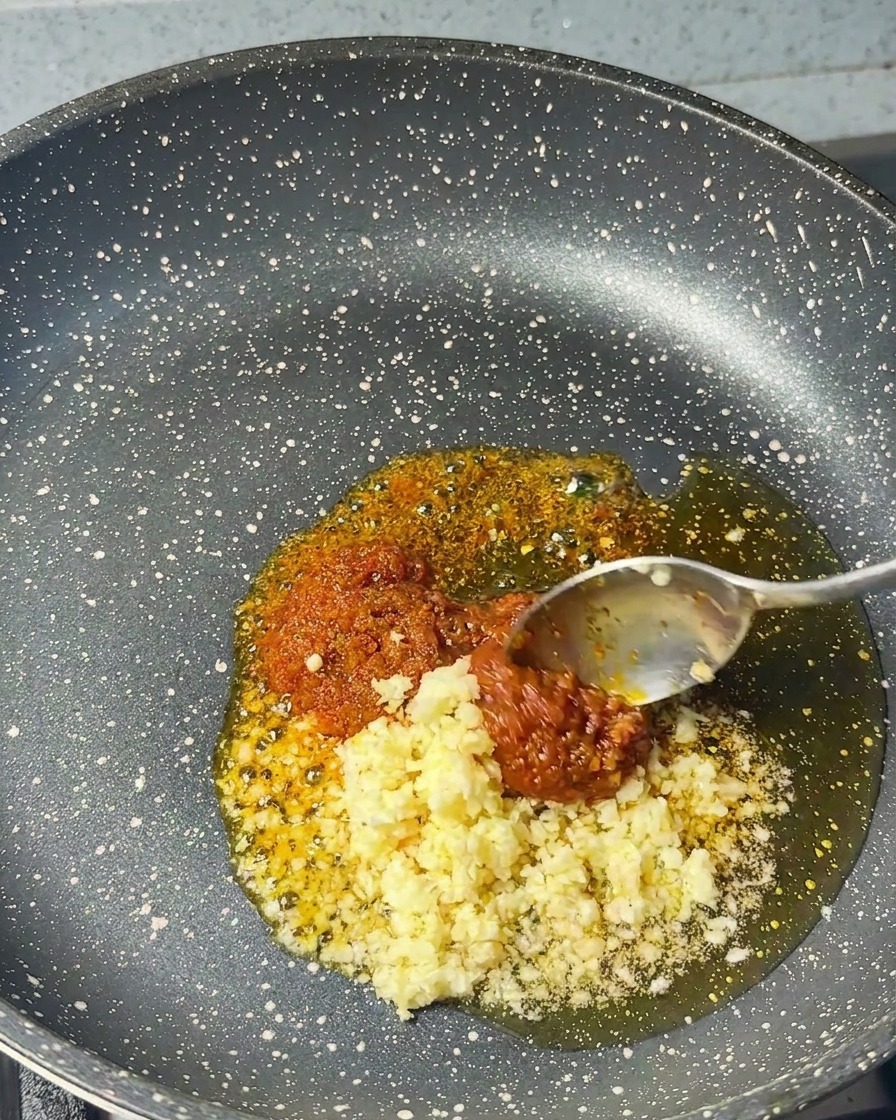 Aglio tritato aggiunto in padella insieme alla pasta di gamberi e allolio di sesamo.
