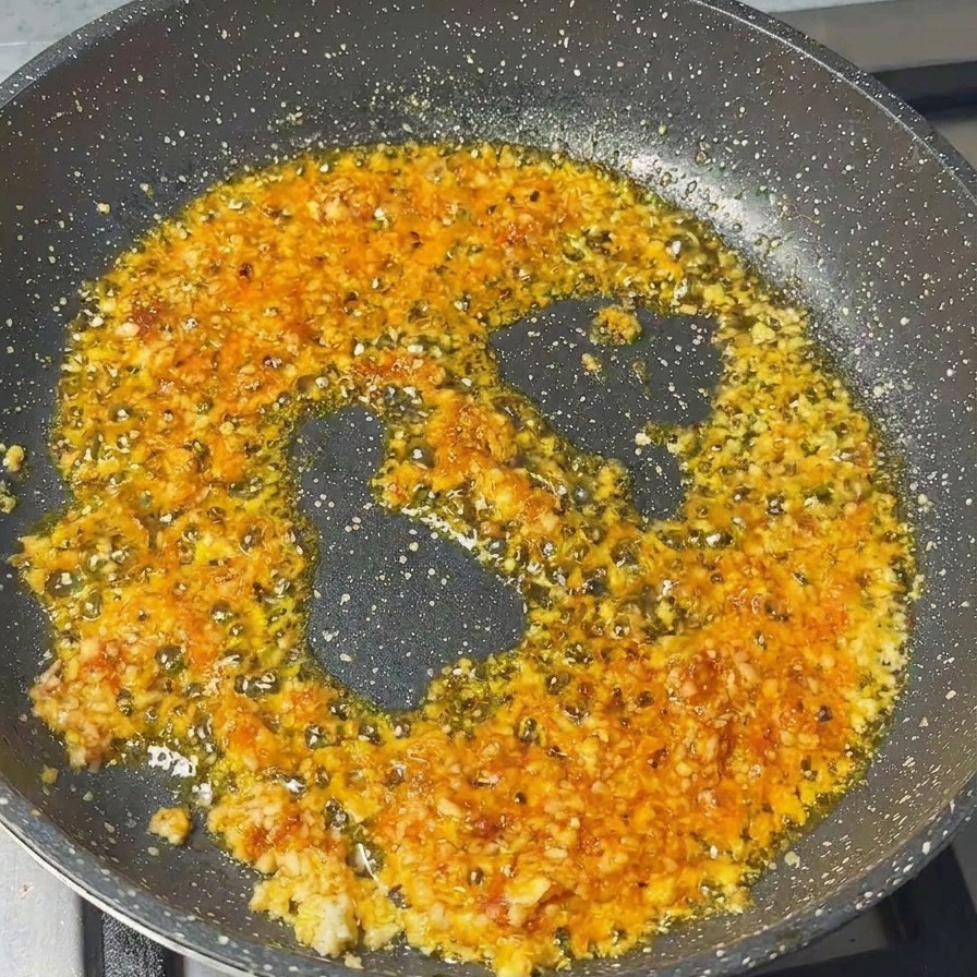 Carne di maiale macinata mescolata in padella con una base di aglio e pasta di gamberi.