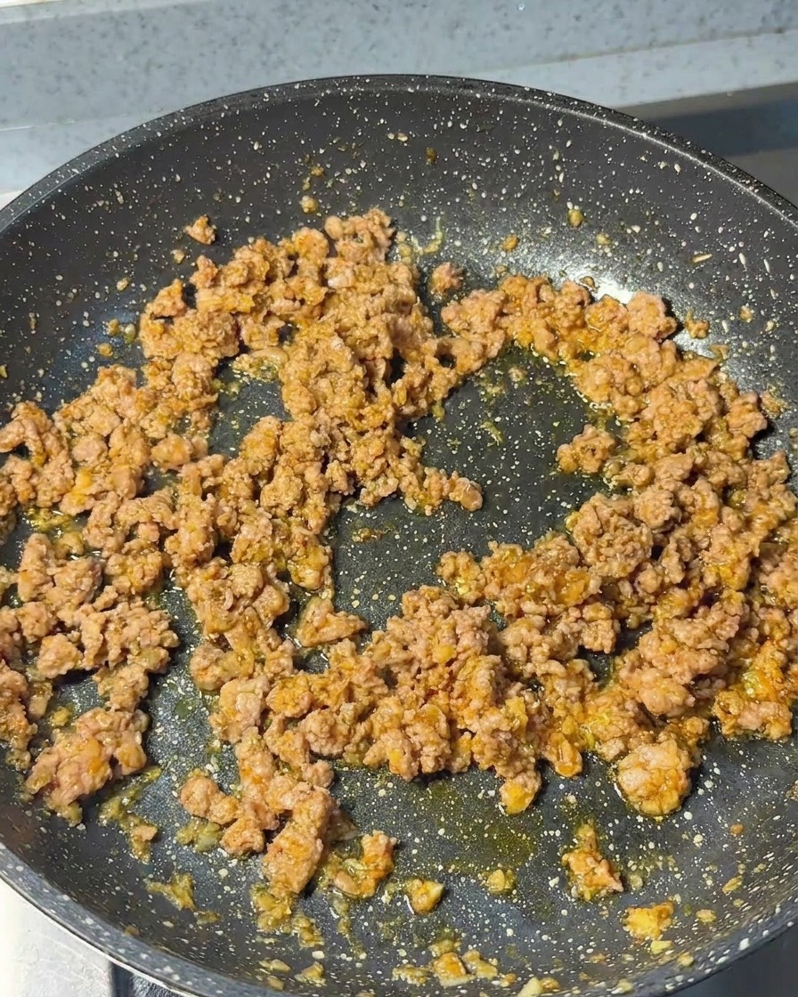 Maiale macinato saltato in padella, con una consistenza ben rosolata e sgranata.