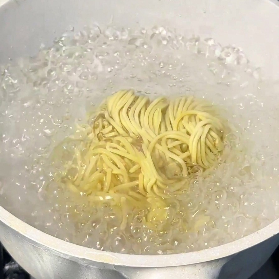 Noodles per ramen giapponesi cotti in una pentola con acqua in vivace ebollizione.