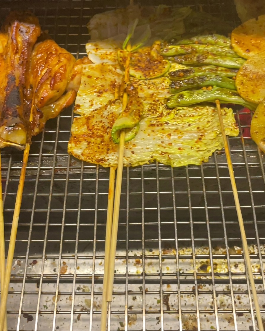 Sovracosce di pollo, cavolo, zucchine, fagiolini e fette di patate sulla griglia.