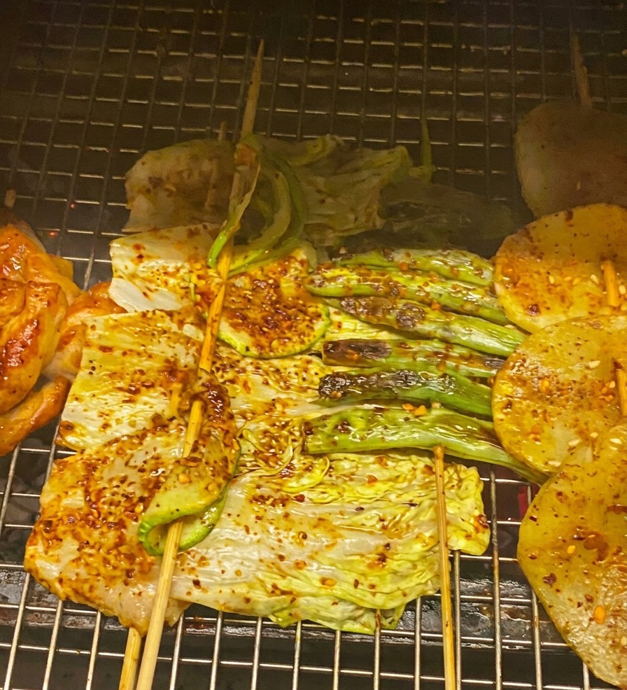 Primo piano di pollo, cavolo e zucchine grigliati spennellati con salsa BBQ rossa e guarniti con cipollotto.