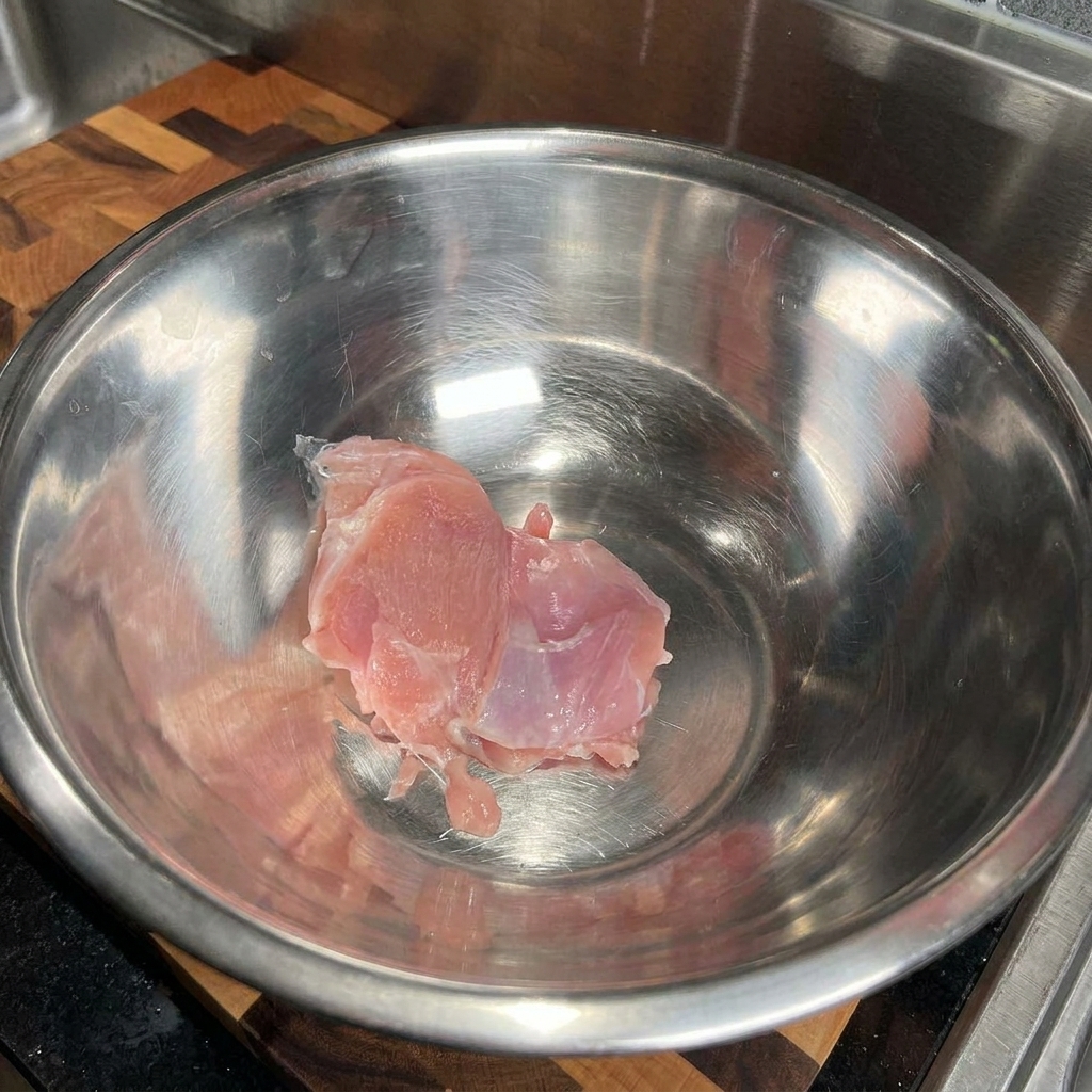 Sovracoscia di pollo cruda in una capiente ciotola di acciaio inox vuota.