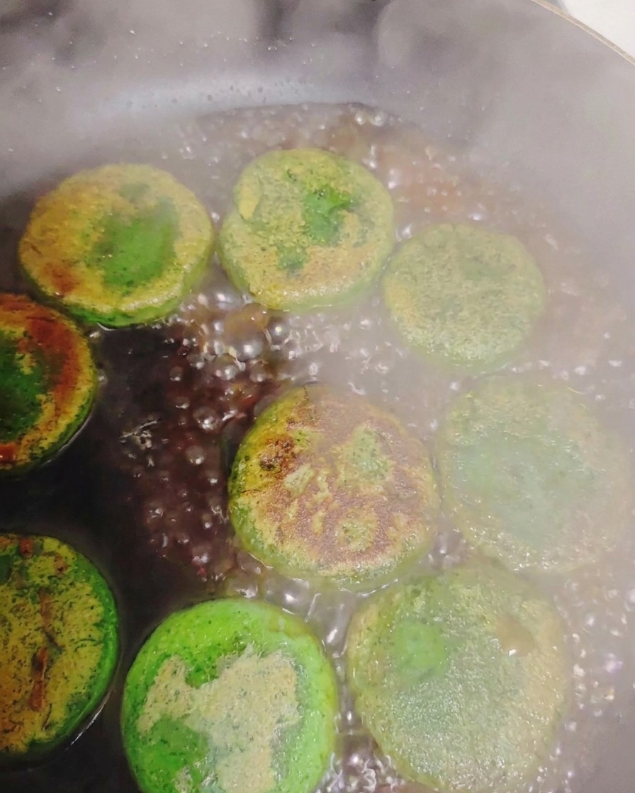 Acqua che sobbolle creando vapore attorno ai pancake alle verdure rosolati allinterno di una padella calda.