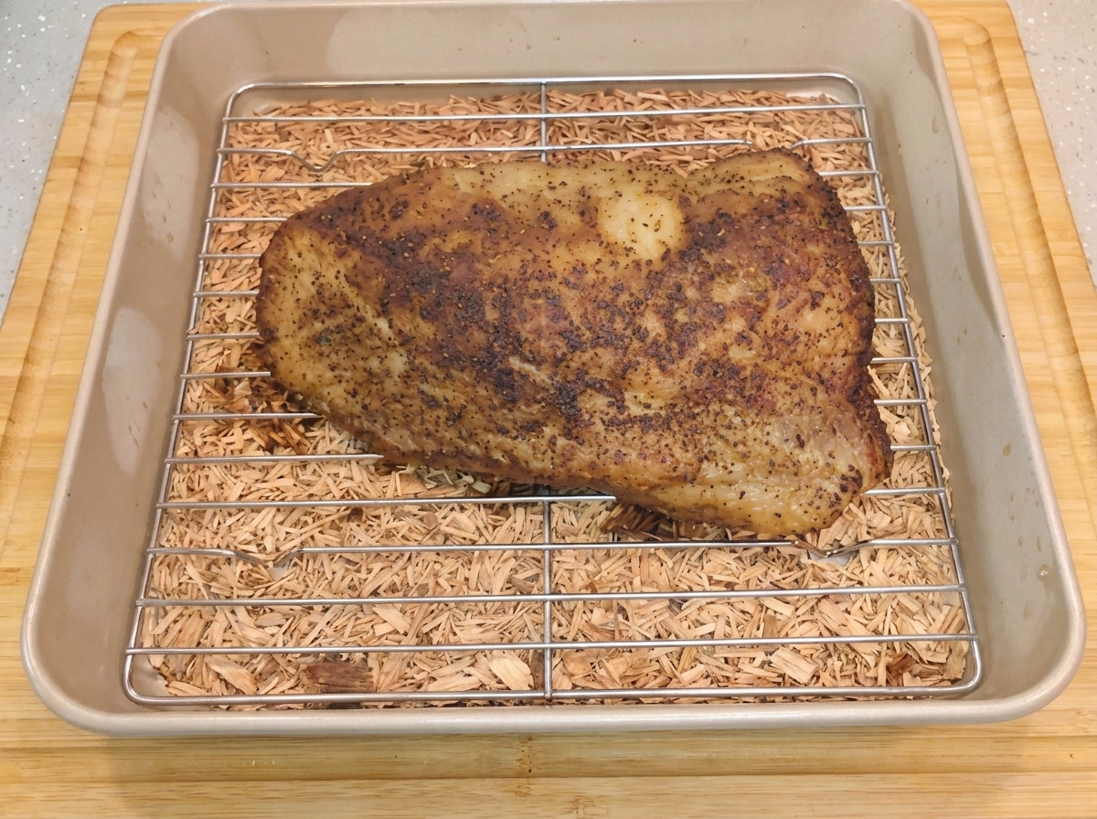 Il brisket di manzo speziato e fumante riposa sulla griglia metallica allinterno della teglia dopo la rimozione dellalluminio.