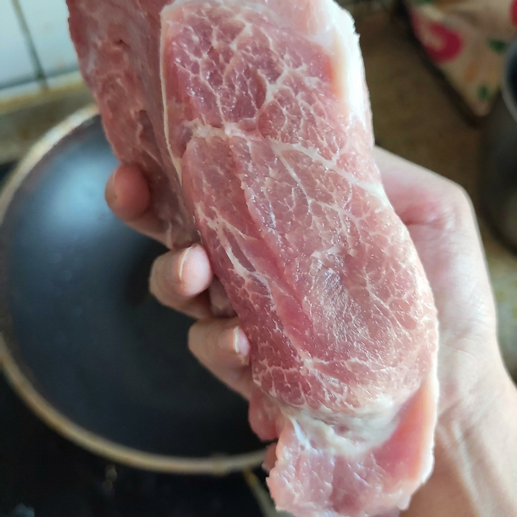 Un pezzo di coppa di maiale cruda e ben marezzata mostra la sua freschezza e la distribuzione del grasso.