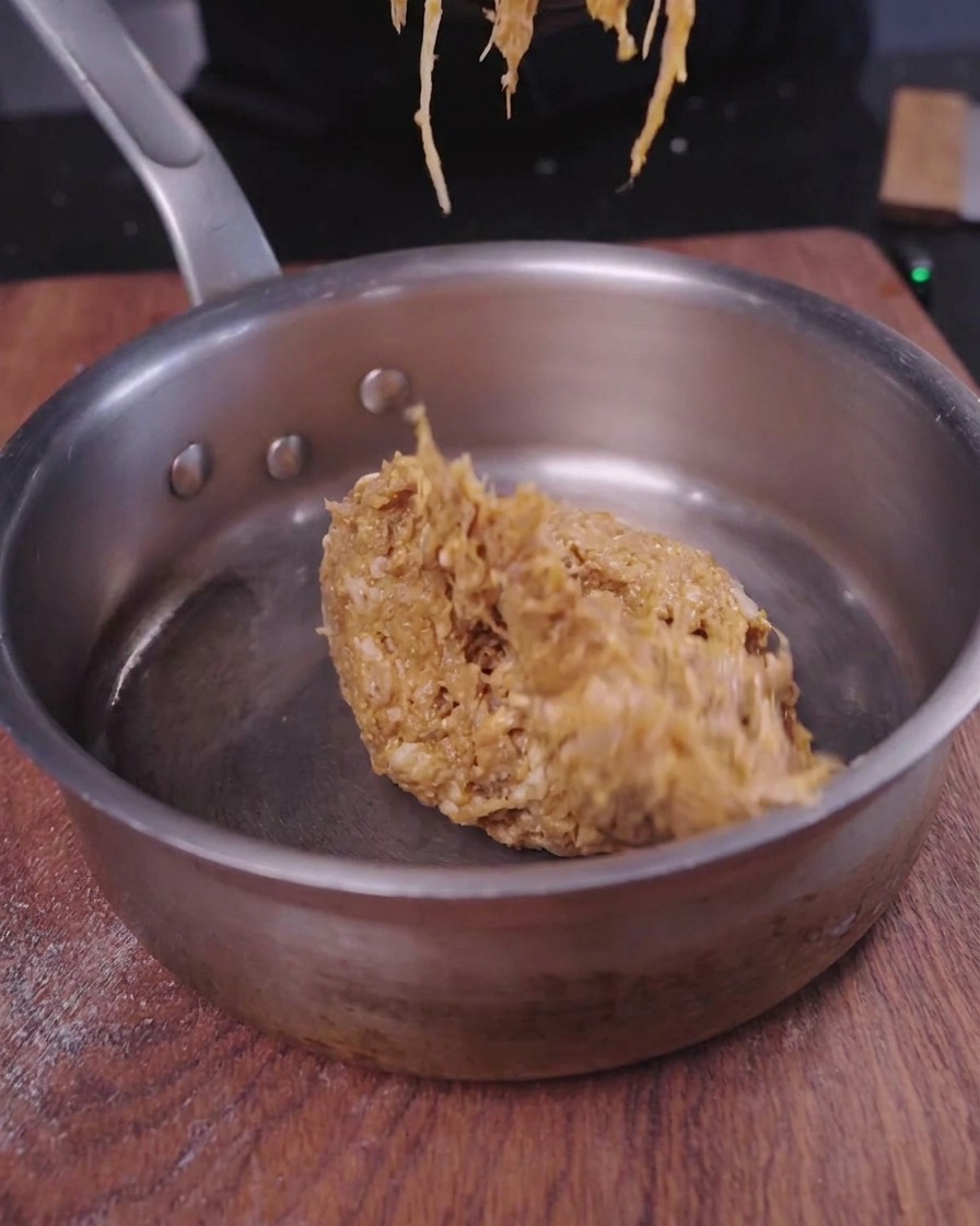 Una porzione di saporito pulled pork sfilacciato che viene scaldata allinterno di un piccolo pentolino di metallo.
