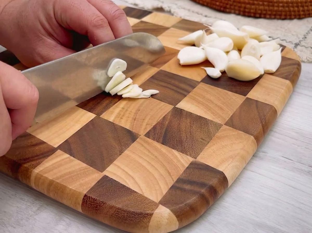 Pezzetti di aglio tritato finemente sparsi su un tagliere di legno.