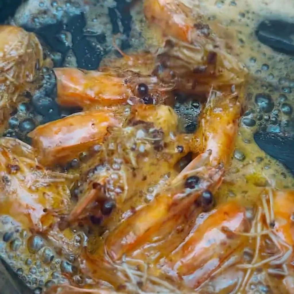 Teste di gambero sollevate dallolio aromatizzato usando bacchette da cucina.