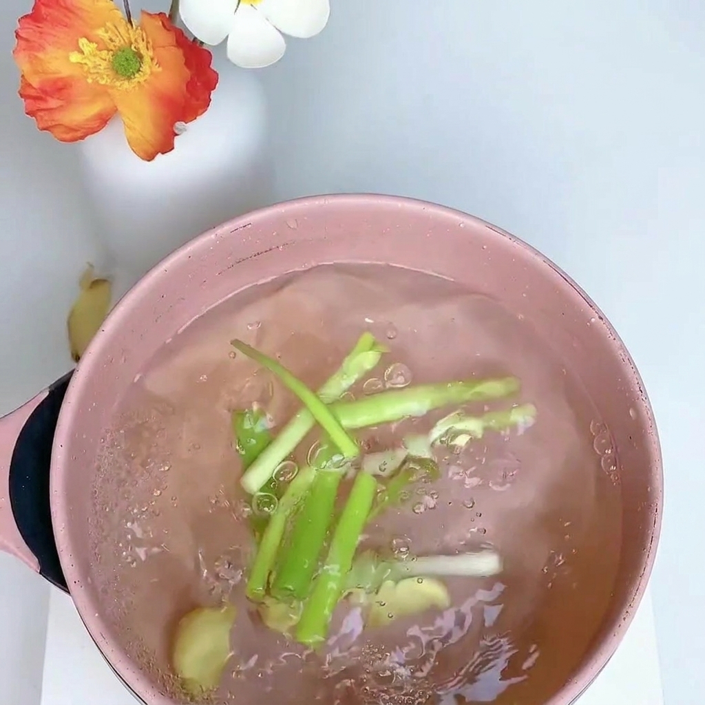 Coscia di pollo in una pentola dacqua con cipollotti, zenzero e anice stellato.