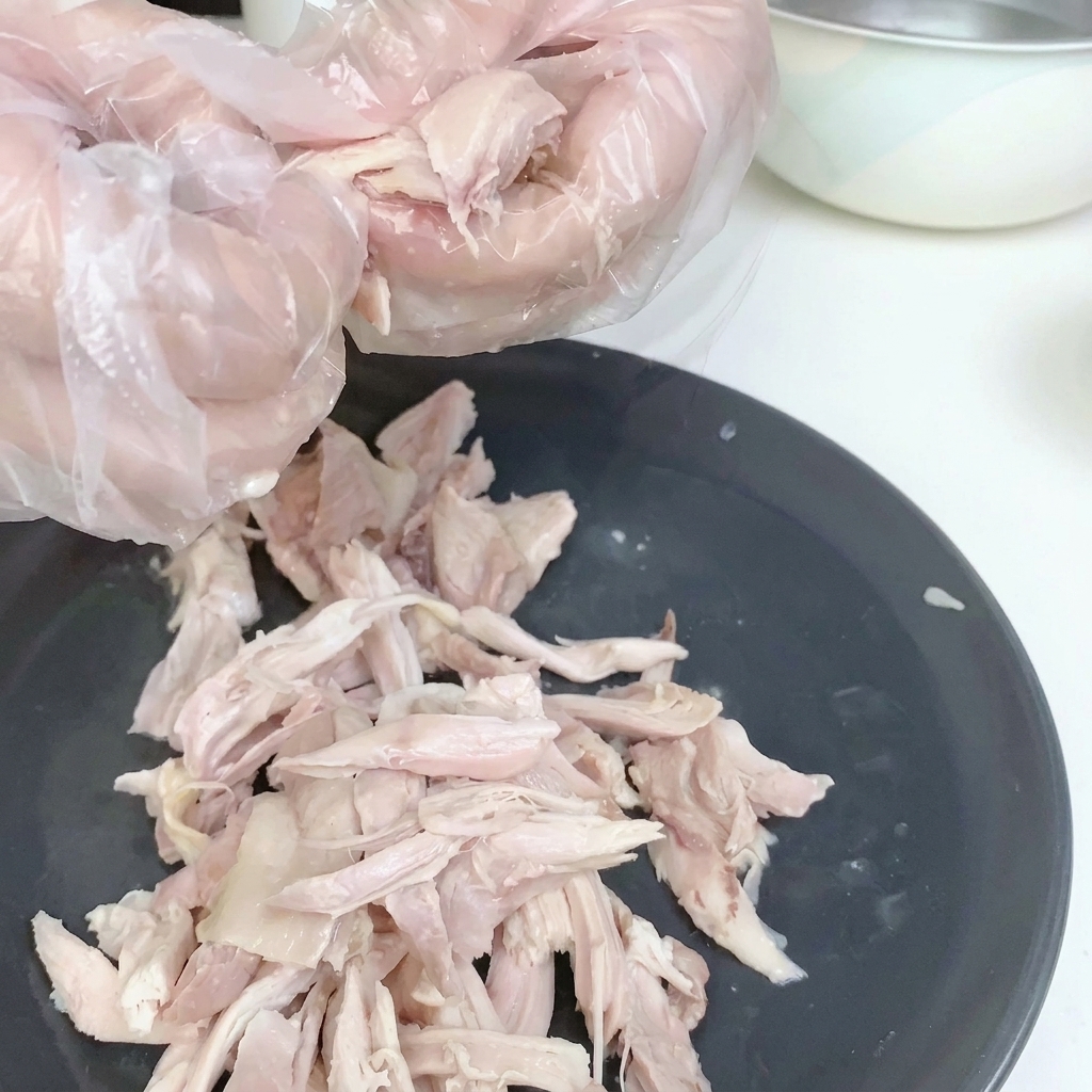 Pollo sfilacciato su un piatto bianco, senza pelle.