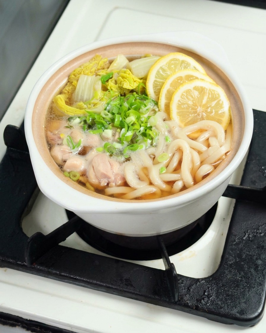 Fette di limone giallo fresco posizionate con cura sopra una ciotola fumante di noodles udon.
