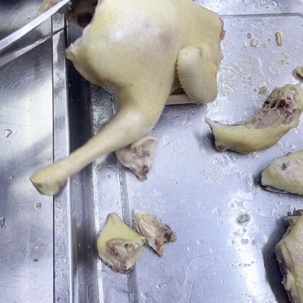 Un paio di forbici da cucina che tagliano il pollo cotto su una superficie in acciaio inox.