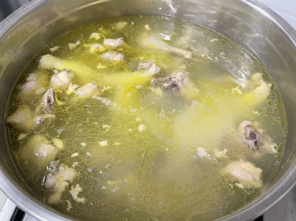 Condimento cosparso in una pentola di brodo di pollo dorato che sobbolle.