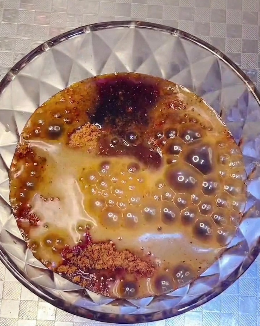 Una salsa scura e saporita versata dalla ciotola nella pentola con gli ingredienti.