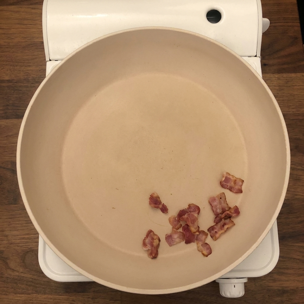 Cipolle fresche tritate e sedano vengono aggiunti alla padella con pezzi di pancetta croccante.