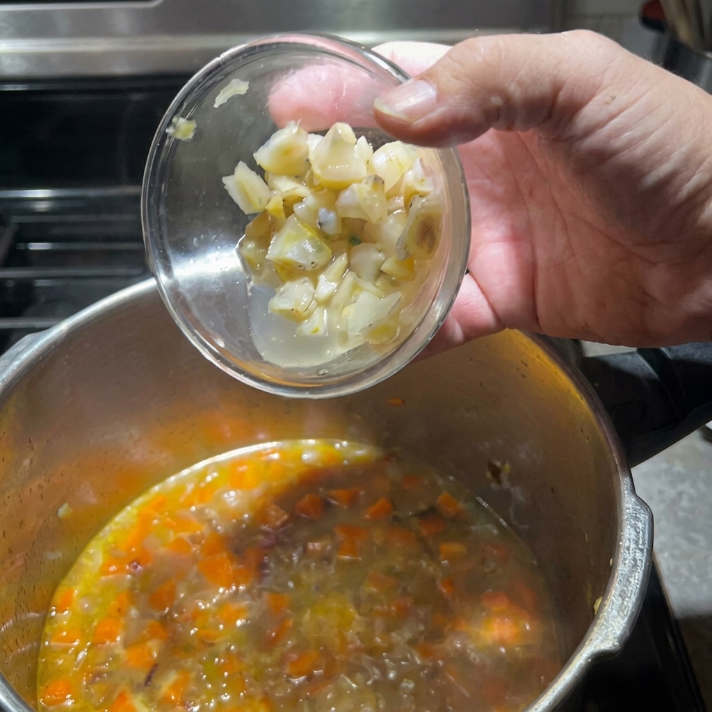 Aggiunta dei pezzi di vongole preparati nella pentola con le verdure.