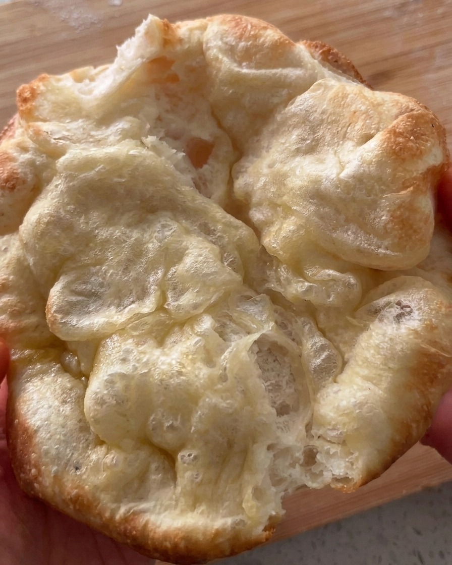 Pane pizza appena sfornato e piegato a metà che viene aperto con cura.