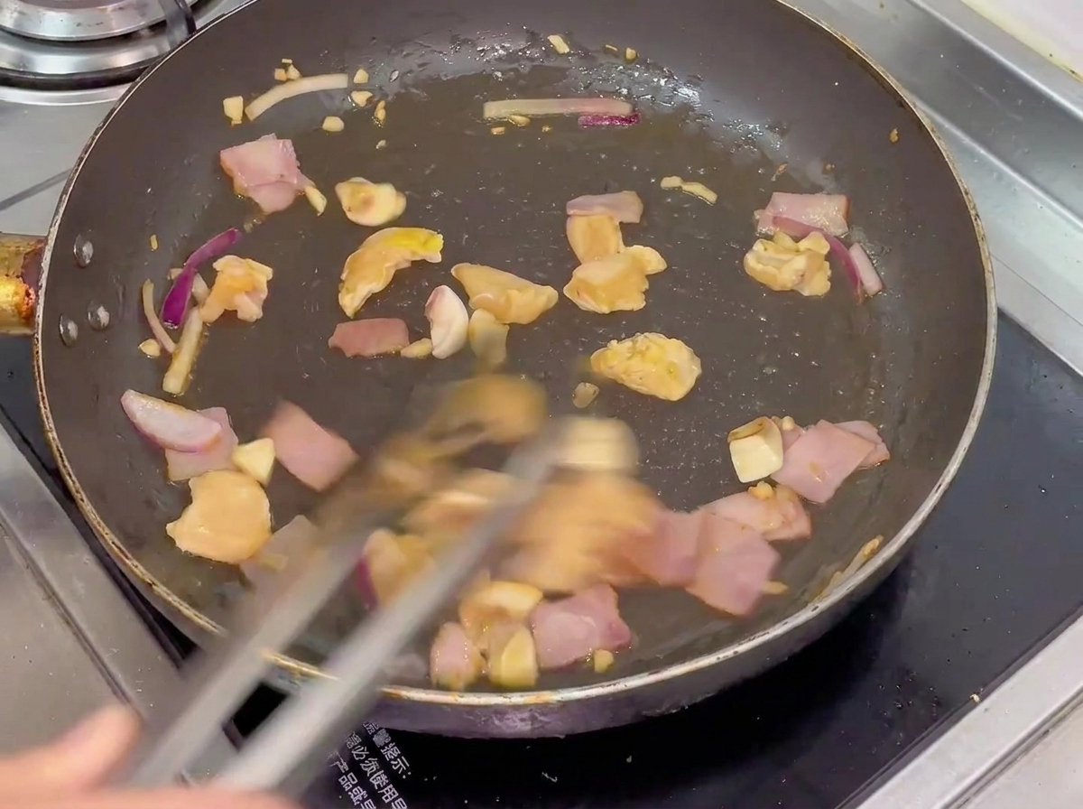 Pollo, pancetta, funghi e cipolla che soffriggono in padella.