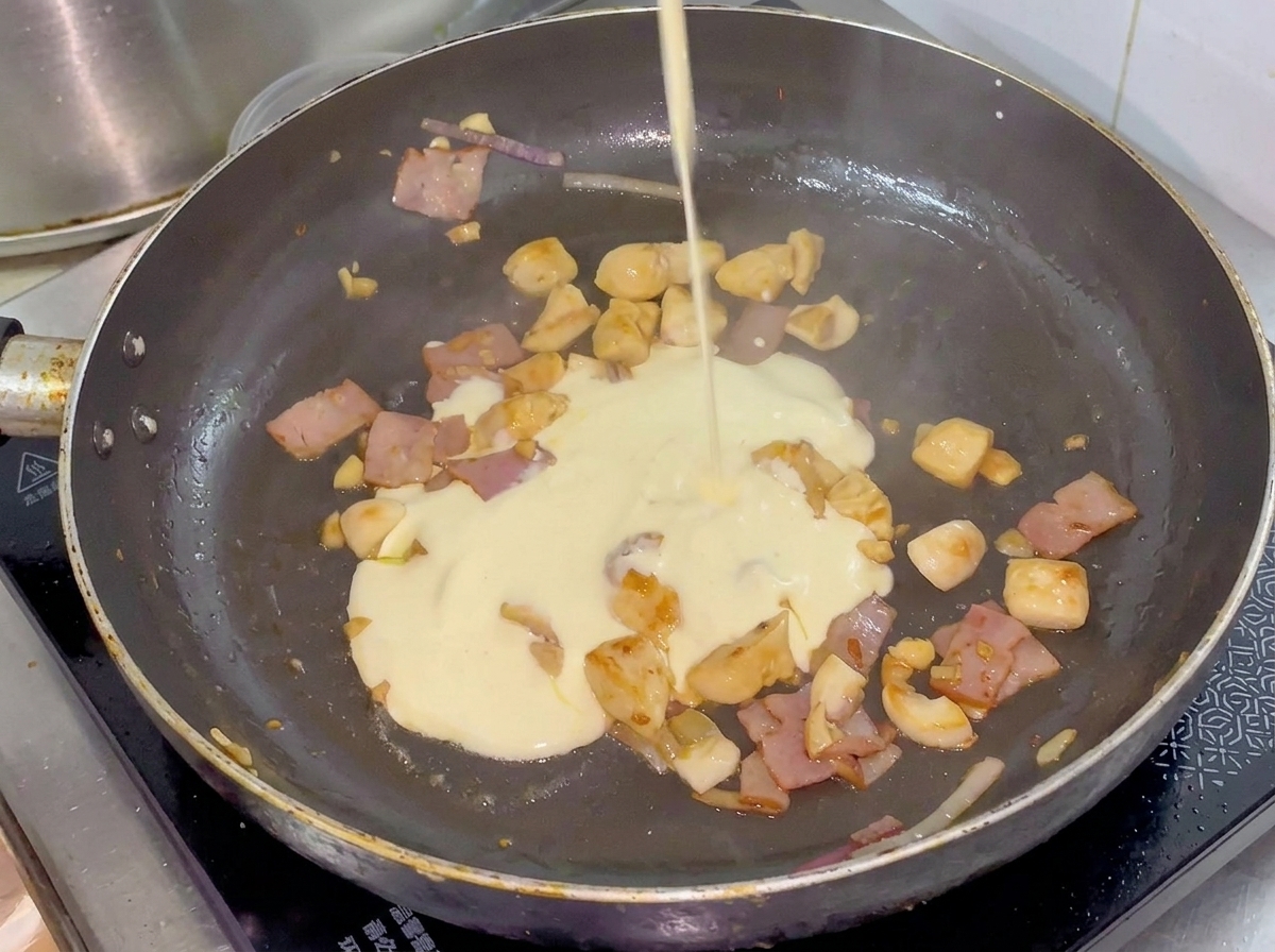 Panna versata in padella sopra il pollo, la pancetta e le verdure.