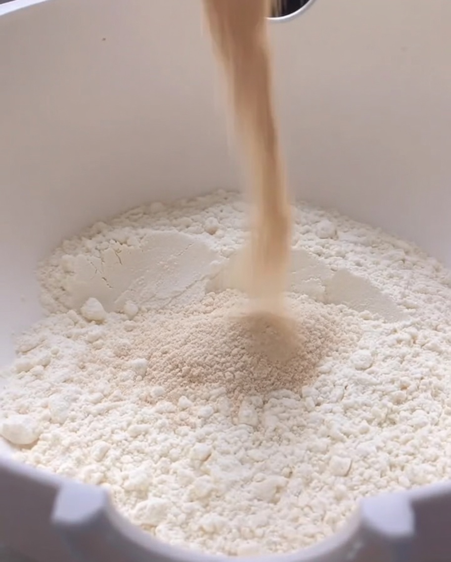 Lievito secco versato in una grande ciotola bianca contenente farina.