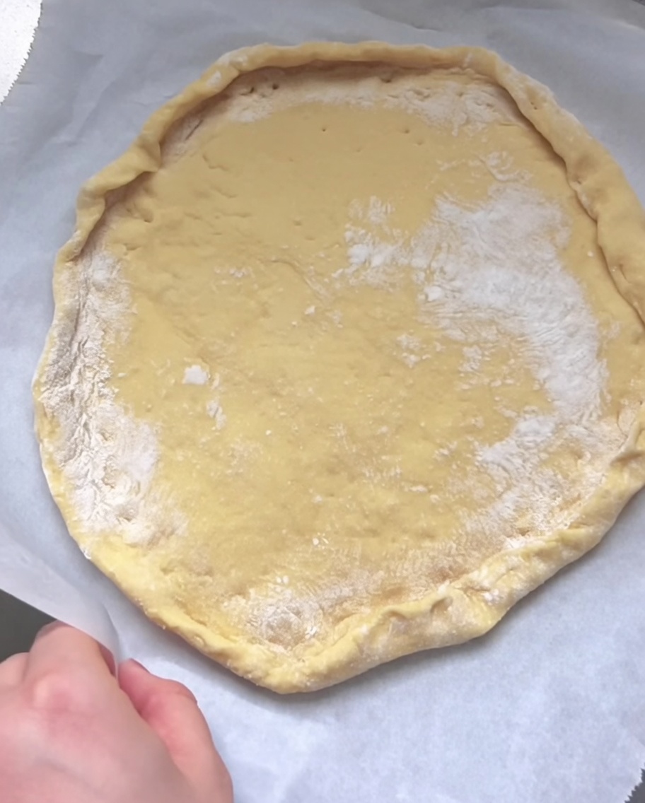 Una mano ripiega e pizzica il bordo dellimpasto per formare il cornicione.