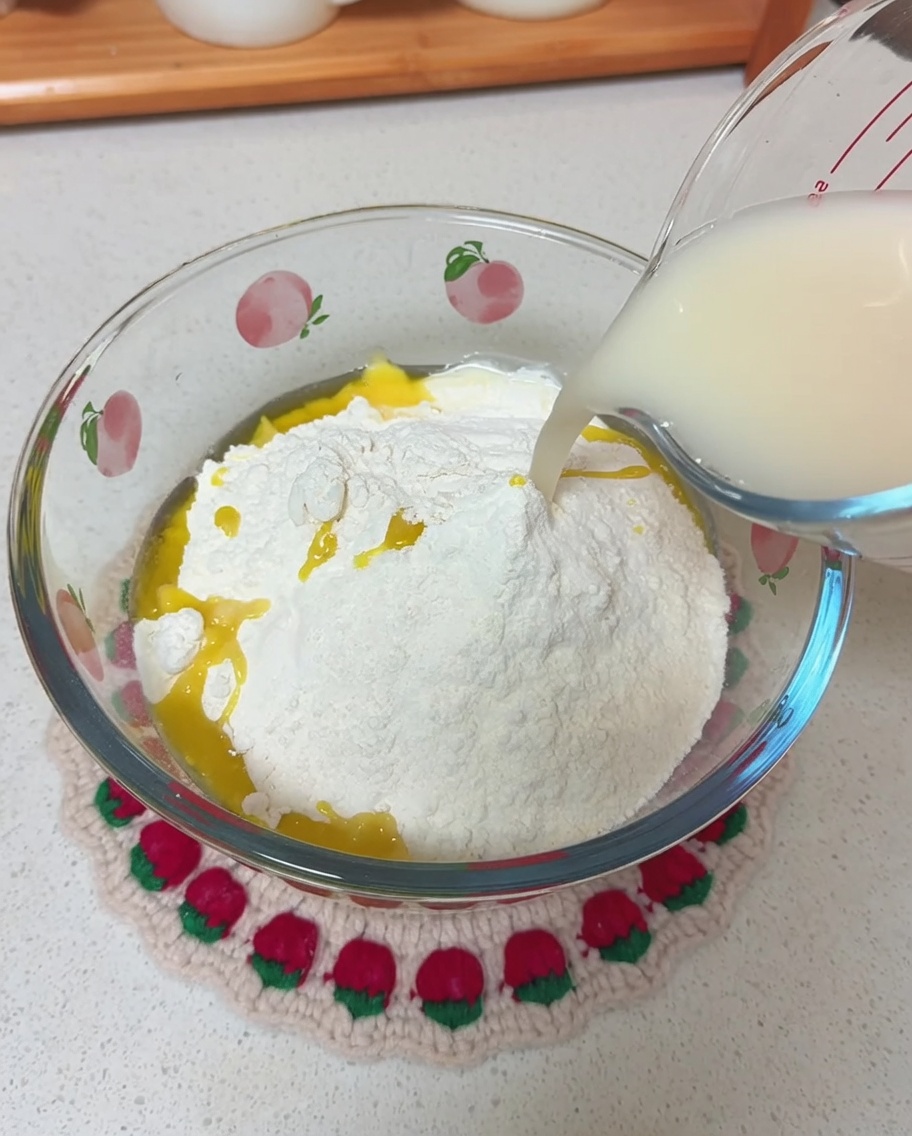 Versamento del composto di acqua e lievito in una ciotola contenente farina e olio.